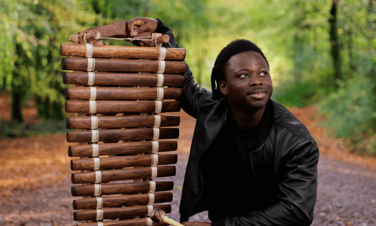 N'famady Kouyaté holding an instrument outside.